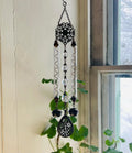 Decorative hanging ornament with beads and crystals in front of a window