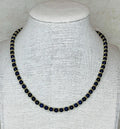 Necklace with blue beads on a mannequin bust against a neutral background