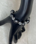 Black beaded bracelet on a black mannequin arm against a light background