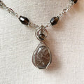 Necklace with a pendant featuring a teardrop-shaped stone on a beige fabric background