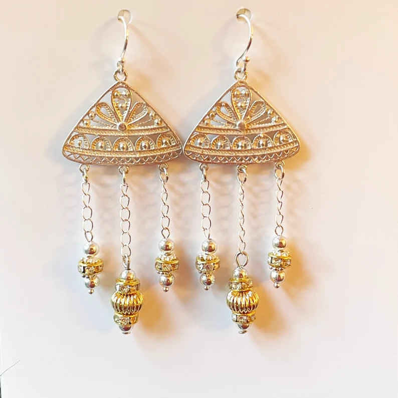 Gold triangle-shaped earrings with dangling beads on a light background