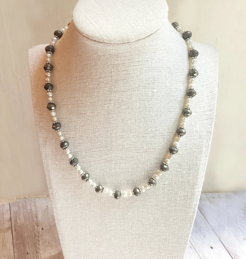 Necklace with alternating black and white beads on a mannequin bust.