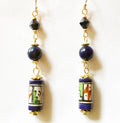 Pair of earrings with blue beads and colorful cylindrical charms on a white background