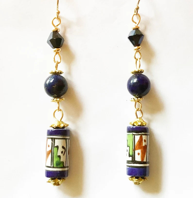 Pair of earrings with blue beads and colorful cylindrical charms on a white background