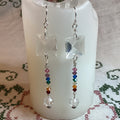 Colorful beaded earrings on a white candle with a patterned fabric background