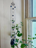 Decorative hanging crystal with blue stones near a window