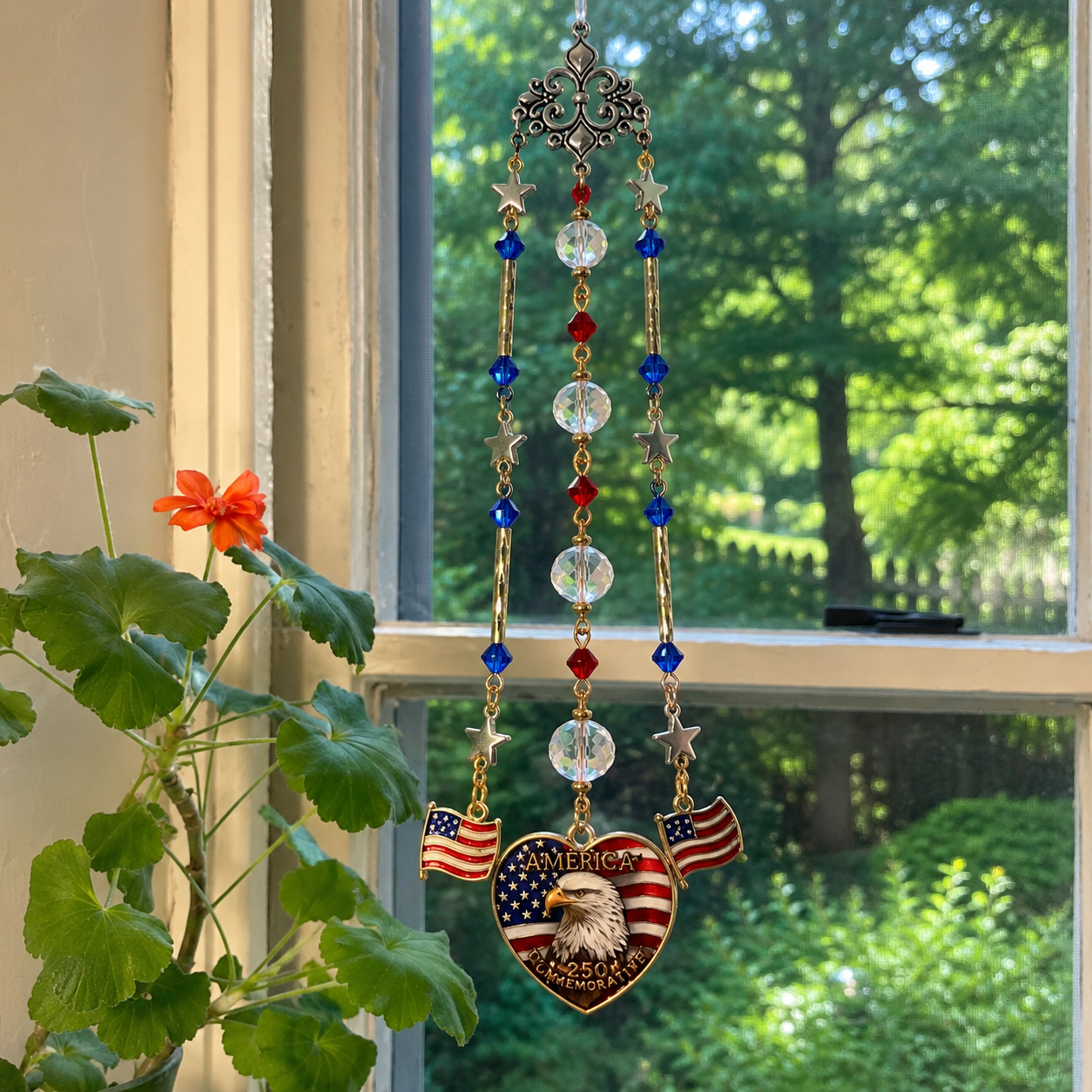 Handmade America 250 commemorative suncatcher featuring a Bald Eagle, American flag heart pendant, crystal prisms, and patriotic red, white, and blue accents hanging in a window.