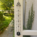 Handmade Capricorn zodiac suncatcher featuring a Black Agate gemstone pendant, crystal beads, and silver angel wing accents hanging in a sunlit window.