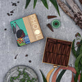 A box of Phool Eucalyptus Incense Cones with incense cones visible inside the open box, surrounded by foliage and a decorative item.