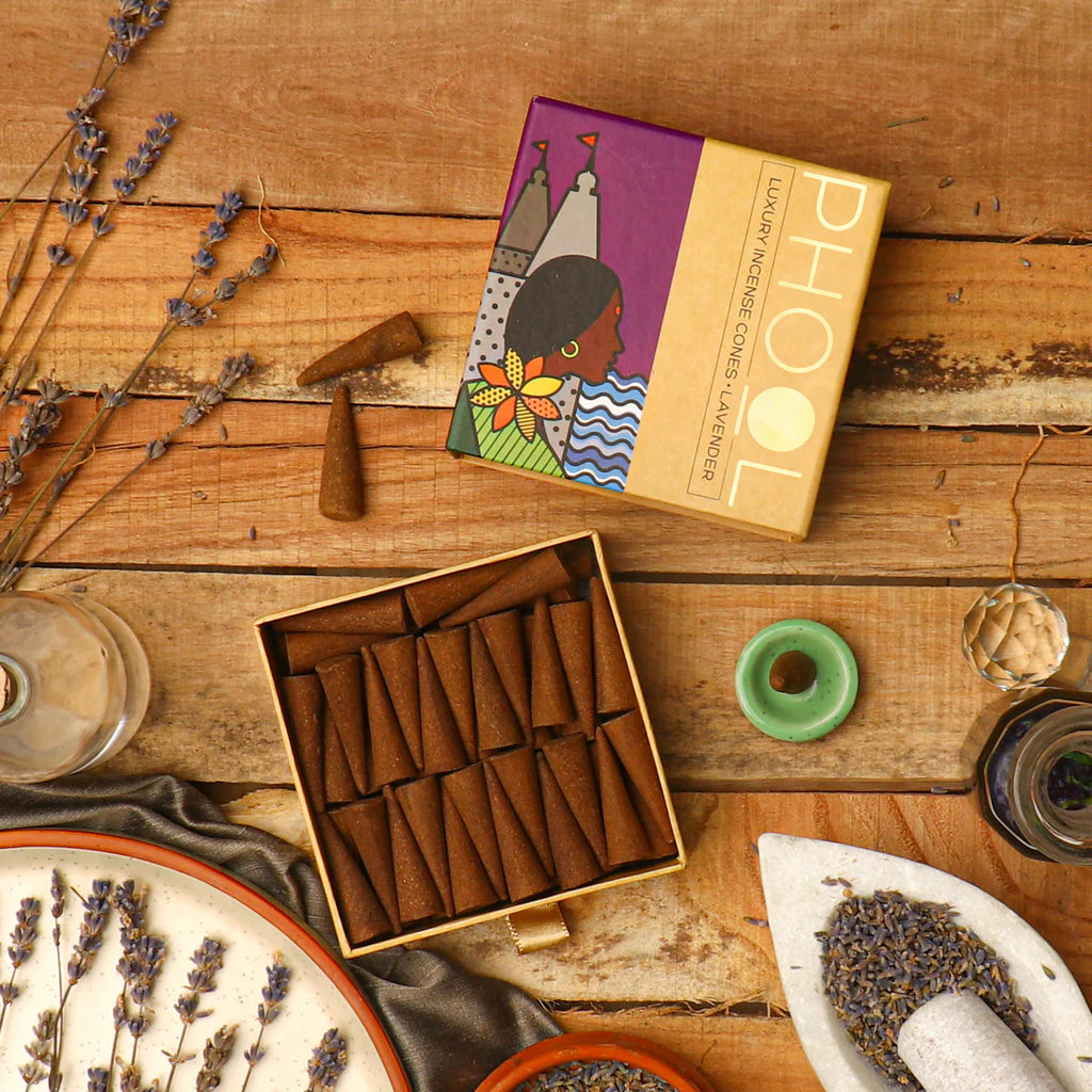 A box of Phool Lavender Incense Cones displayed on a wooden surface, with the brand name 'TOH' visible on the packaging. The cones are arranged in a rectangular pattern inside the box, and there are lavender flowers and incense accessories around the box.