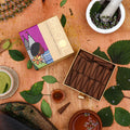 A box of Phool Patchouli Incense Cones displayed alongside natural elements such as leaves and spices, indicating the earthy aroma of the product.