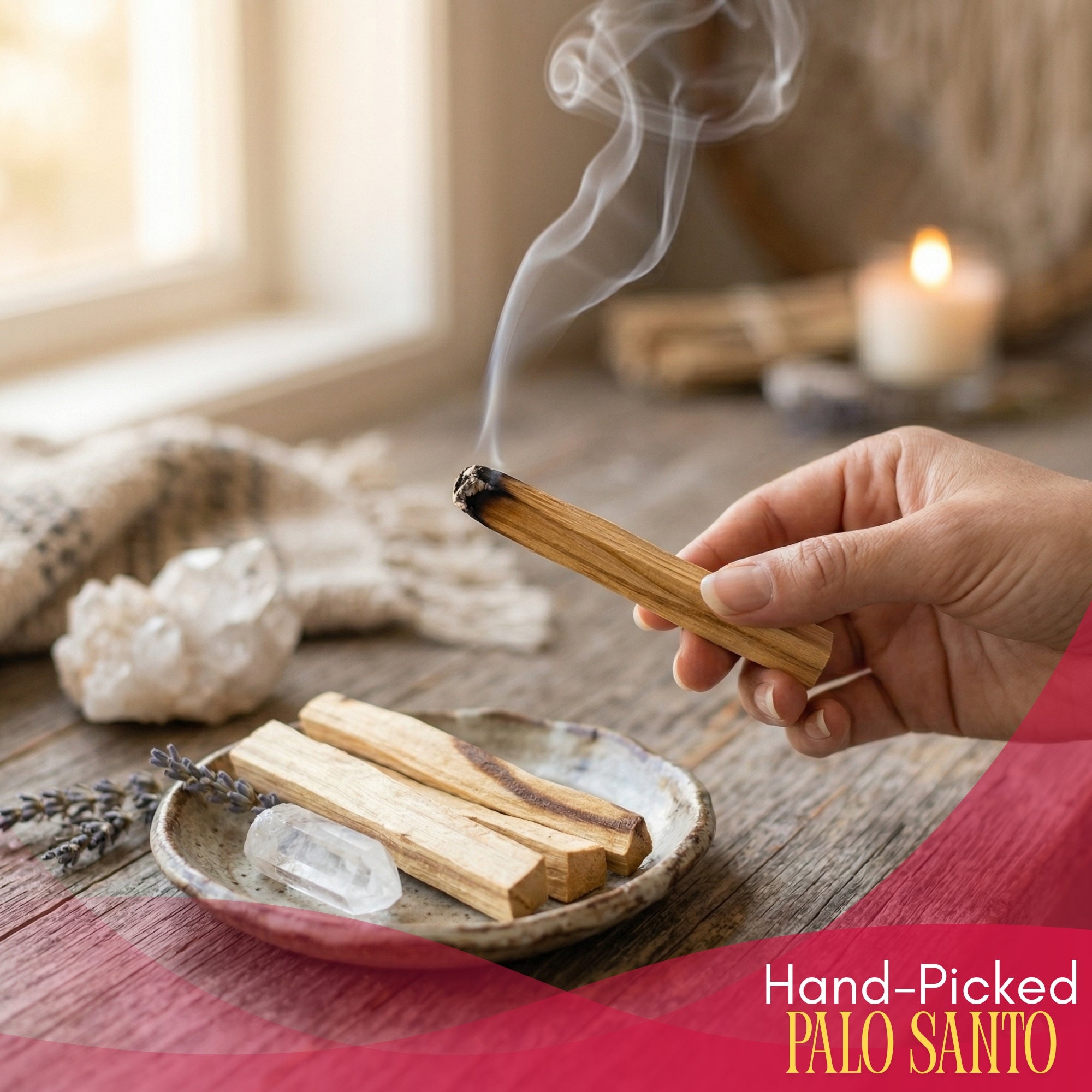 Hand holding a smoldering Palo Santo stick with crystals and candles in the background.