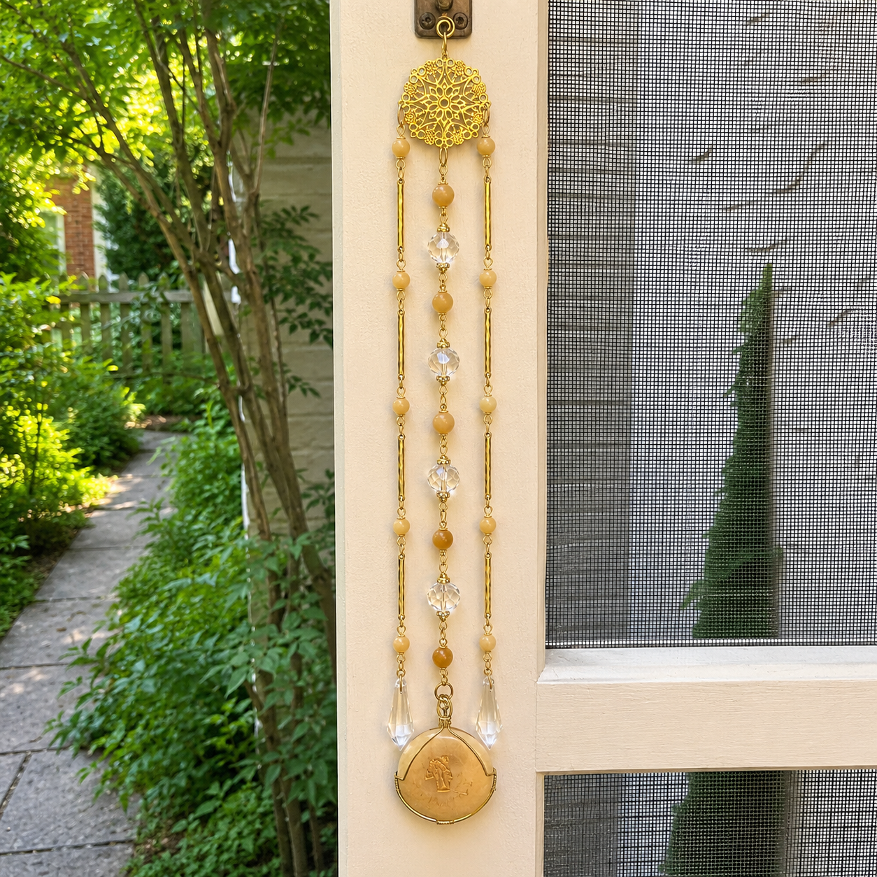 Handmade Leo zodiac suncatcher featuring a Leopard Skin Jasper pendant, crystal prisms, and gold-tone filigree accents hanging in a sunlit window.