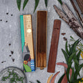 A box of Phool Eucalyptus Incense Sticks alongside several sticks placed outside among leaves and wooden debris, suggesting a natural setting.