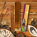 A box of Phool Lavender Incense Sticks displayed alongside a stick partially dipped in a bowl, with lavender flowers and packaging in the background.
