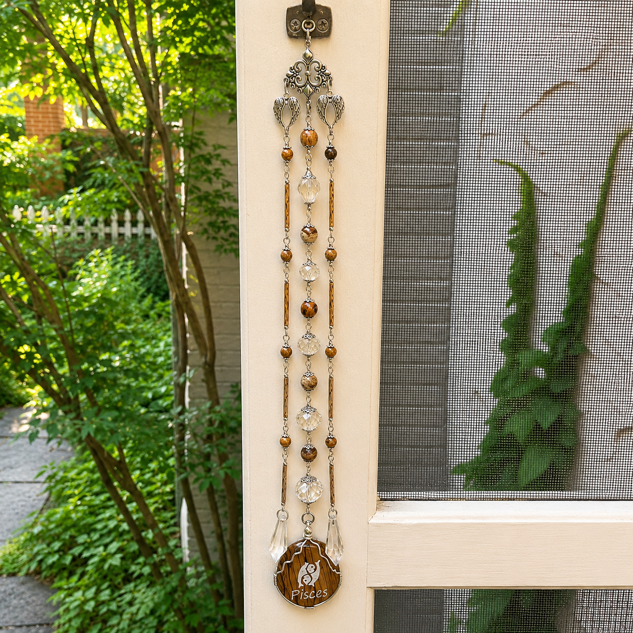 Handmade Pisces zodiac suncatcher featuring a Picture Jasper pendant, crystal prisms, and silver angel wing accents hanging in a sunlit window.