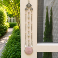 Handmade Virgo zodiac suncatcher featuring a Rose Quartz pendant, crystal prisms, and silver angel wing accents hanging in a sunlit window.