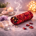 Incense bundle with smoke, candle, crystals, and stones on a textured surface.