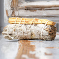Sage bundle with wooden sticks tied together on a reflective surface