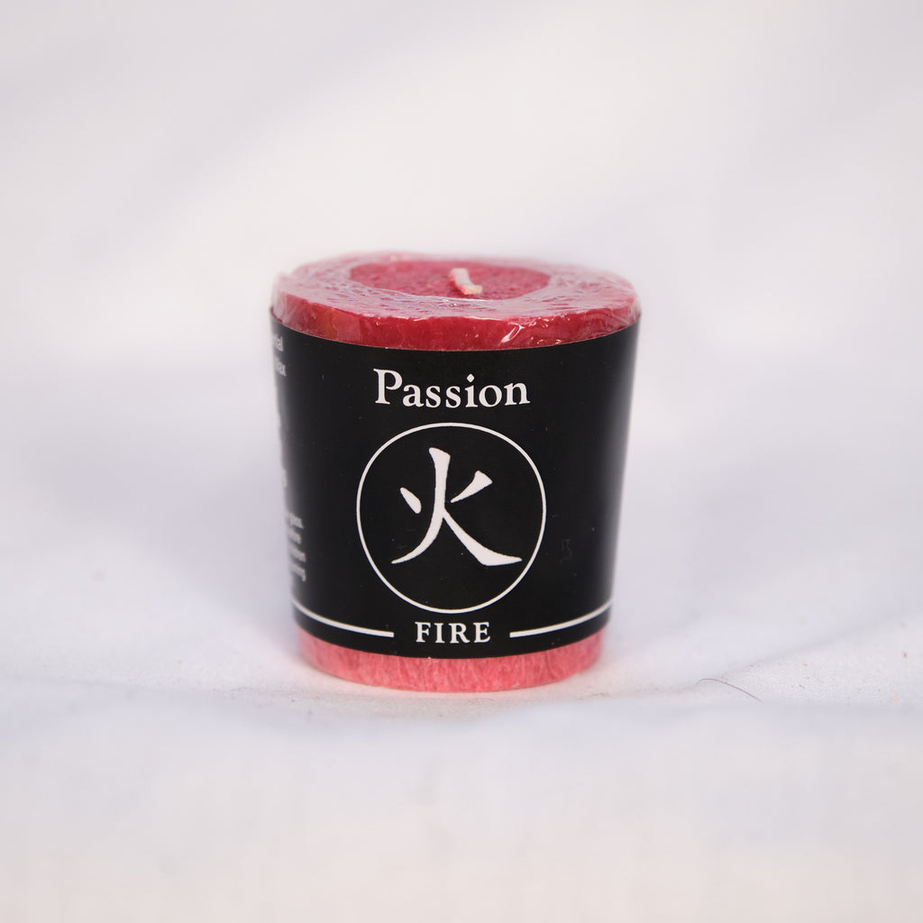 Five lit votive candles with colored labels indicating different qualities such as Success, Creativity, Passion, Wealth, and Inner Peace, arranged on a dark surface.