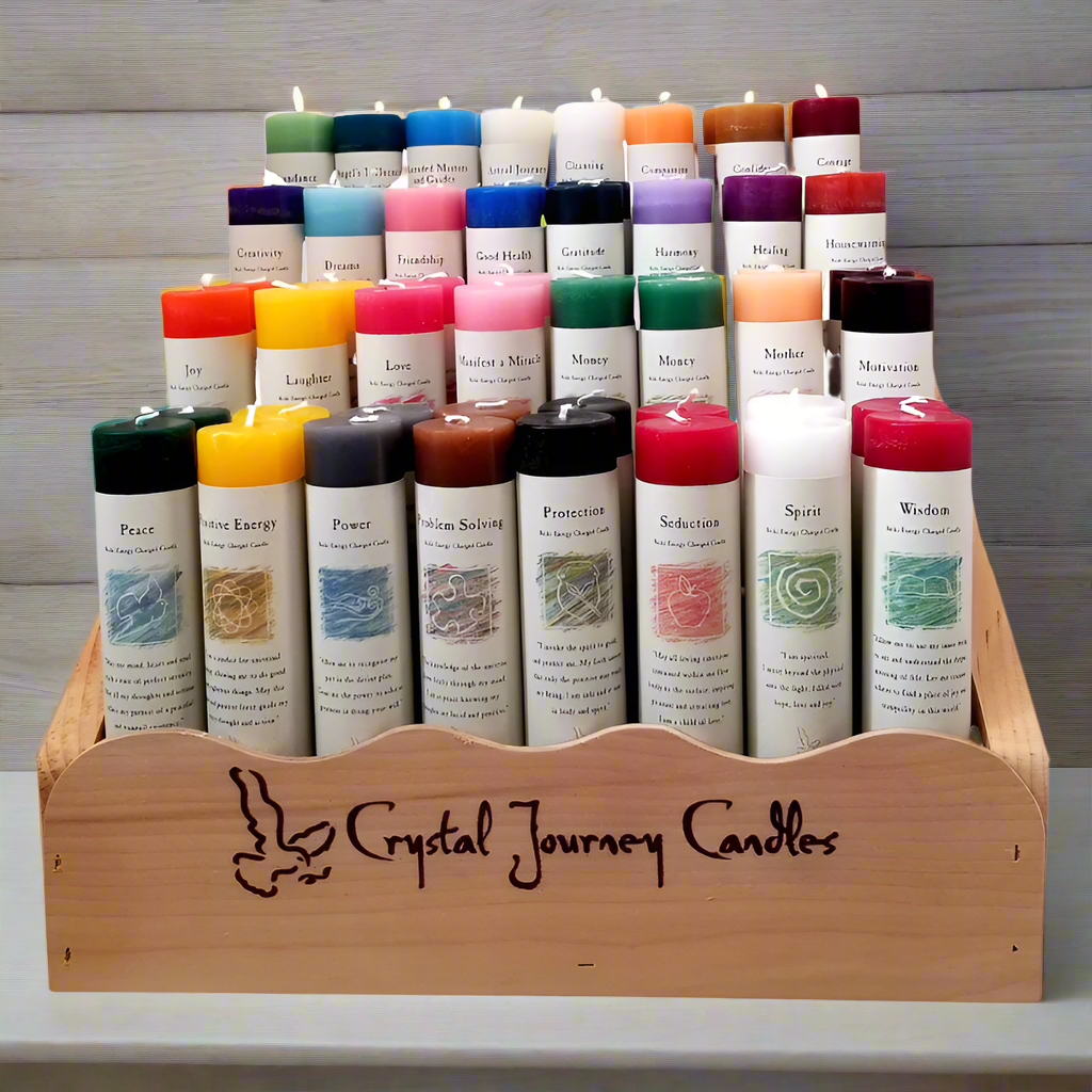 A display of various colored pillar candles in a wooden holder, each labeled with different names such as 'Abundance', 'Angel Influence', 'Astral Journey', etc., indicative of different spiritual or affirmational purposes.